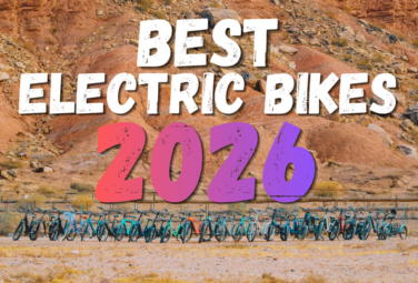 Banner reading "Best Electric Bikes 2026" with colorful 2026 typography above a row of electric bikes parked in a desert landscape.
