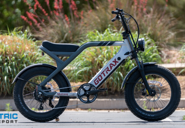 Side view of an electric fat-tire bike parked in a lot; gray frame, black components, and chunky tires.