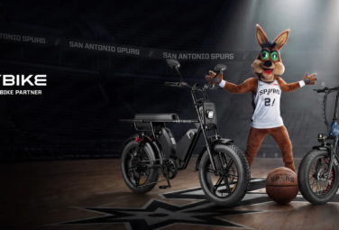 Promotional banner: two Heybike electric bikes on a basketball court with a Spurs mascot in a jersey under spotlights.