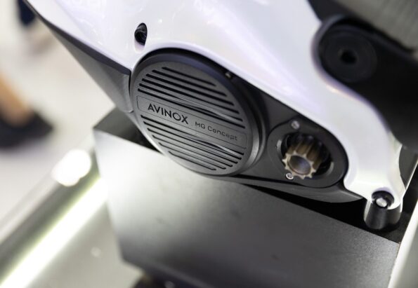 Close-up of a white motorcycle frame with a black round cover labeled 'AVINOX MG Concept'