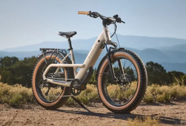 Electric fat-tire bike on a dirt trail with a blue mountain backdrop.
