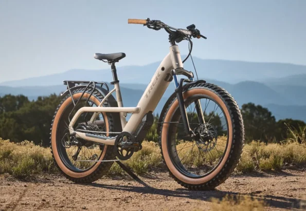 Electric fat-tire bike on a dirt trail with a blue mountain backdrop.